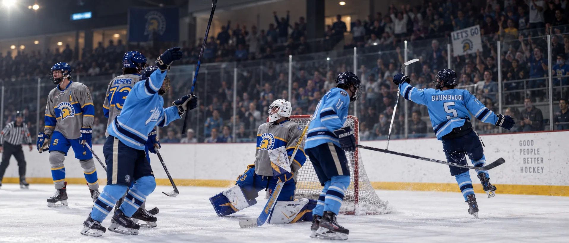 WWU Hockey players in sky-blue jerseys celebrate a goal at home while the crowd cheers behind the glass